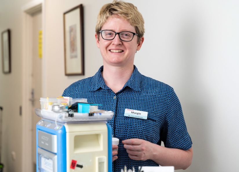 Eldercare Enrolled Nurse smiling at the camera from behind a medication trolley.
